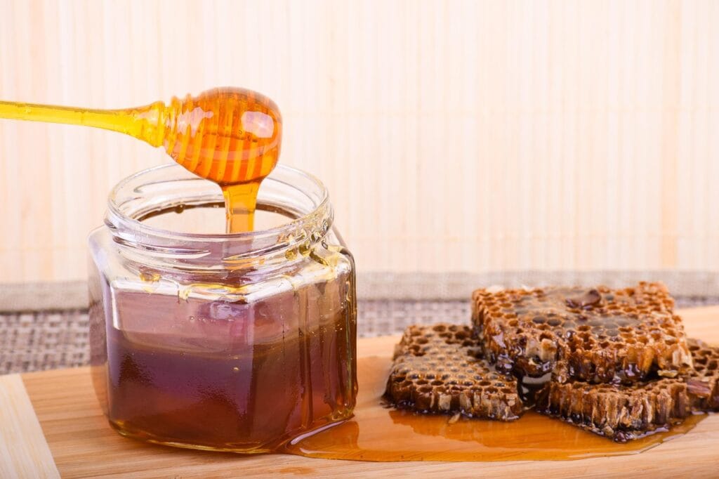 Pure organic urban honey in a glass jar with honeycomb.